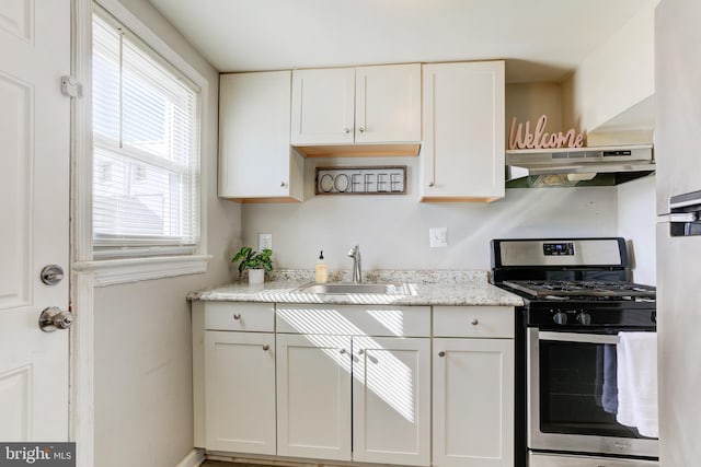 3835 26th Ave, Temple Hills, MD 20748 - kitchen with stainless steel range with gas stovetop, under cabinet range hood, a sink, and white cabinets