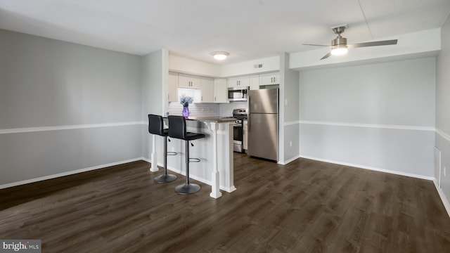 7205 Hilltop Dr Unit 95, Brookhaven, PA 19015 - kitchen featuring stainless steel appliances, a peninsula, a breakfast bar area, white cabinets, and dark wood-style flooring