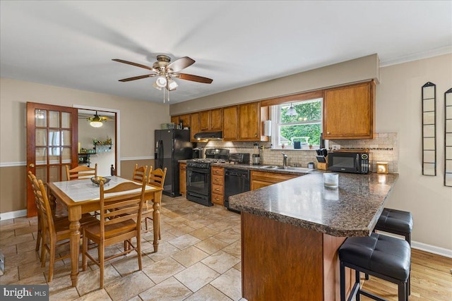 12 Woodlawn Ave, Newfield, NJ 08344 - kitchen featuring black appliances, a peninsula, brown cabinets, ceiling fan, and decorative backsplash
