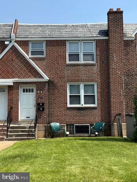 7113 Castor Ave, Philadelphia, PA 19149 - back of property with brick siding, a yard, a high end roof, and a chimney
