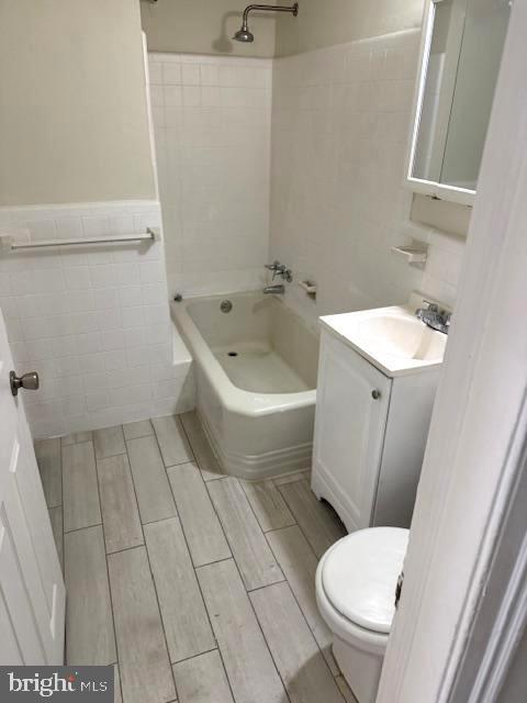 7113 Castor Ave, Philadelphia, PA 19149 - full bath featuring tile walls, vanity, toilet,  shower combination, and a wainscoted wall
