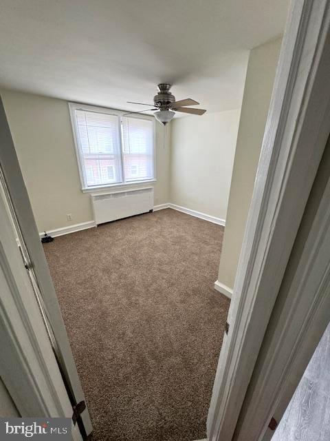7113 Castor Ave, Philadelphia, PA 19149 - empty room with dark colored carpet, a ceiling fan, radiator heating unit, and baseboards