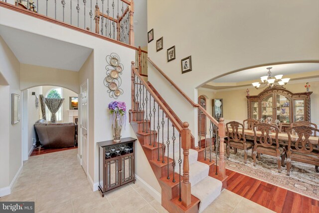 118 Connecticut Ave, Sinking Spring, PA 19608 - stairs featuring arched walkways, a chandelier, a towering ceiling, baseboards, and tile patterned floors