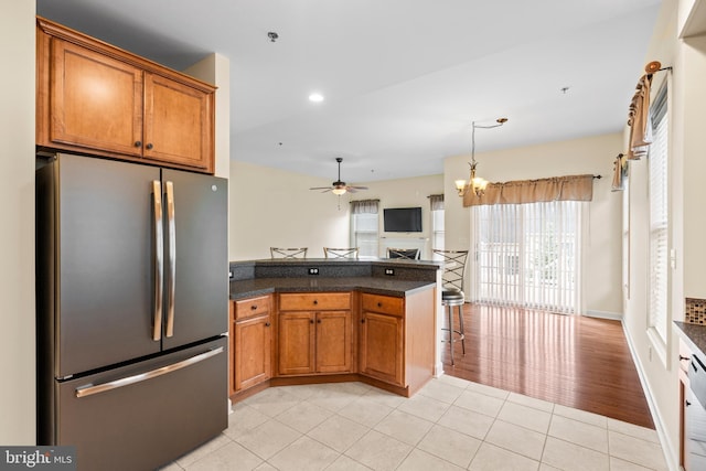 5529 Briar Ln, Whitehall, PA 18052 - kitchen with freestanding refrigerator, a fireplace, brown cabinets, light tile patterned flooring, and ceiling fan