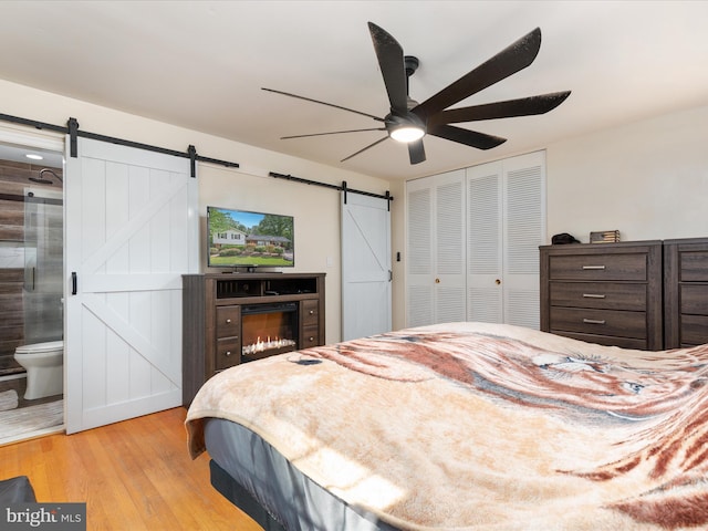 13610 Aden Rd, Nokesville, VA 20181 - bedroom featuring a barn door, light wood finished floors, a closet, ceiling fan, and connected bathroom
