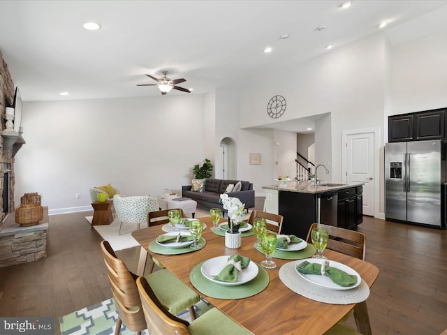 33512 Auburn Dr, Rehoboth Beach, DE 19971 - dining room featuring ceiling fan, arched walkways, dark wood-type flooring, a towering ceiling, and baseboards