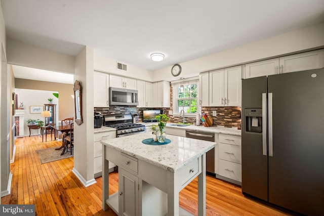 503 Emily Cir, West Chester, PA 19382 - kitchen with appliances with stainless steel finishes, light wood finished floors, backsplash, white cabinetry, and light stone counters