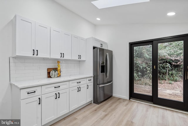 6136 Sinbad Pl, Columbia, MD 21045 - kitchen featuring stainless steel fridge, a skylight, backsplash, light stone counters, and light wood-style flooring
