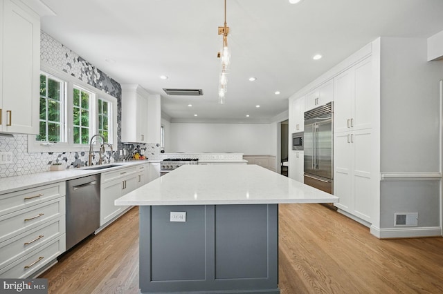 4788 Charter Ct, Woodbridge, VA 22192 - kitchen with built in appliances, backsplash, a kitchen island, white cabinetry, and light wood-style floors