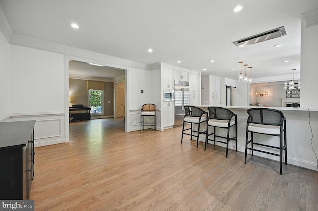 4788 Charter Ct, Woodbridge, VA 22192 - kitchen with built in appliances, crown molding, a kitchen bar, white cabinetry, and pendant lighting