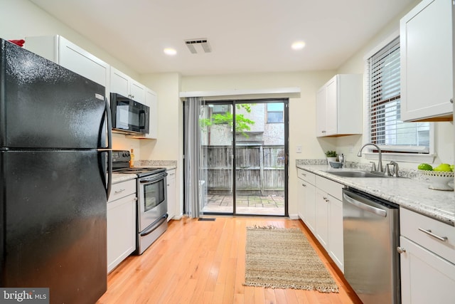 106 W Montgomery St, Baltimore, MD 21230 - kitchen with black appliances, white cabinetry, light wood finished floors, and recessed lighting