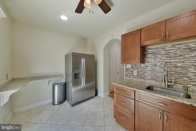 452 Fitzgerald St, Philadelphia, PA 19148 - kitchen featuring stainless steel fridge with ice dispenser, brown cabinetry, ceiling fan, tasteful backsplash, and light stone countertops