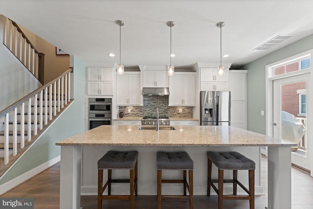 145 Center St S Unit 4, Vienna, VA 22180 - kitchen featuring appliances with stainless steel finishes, decorative backsplash, under cabinet range hood, a kitchen bar, and white cabinets