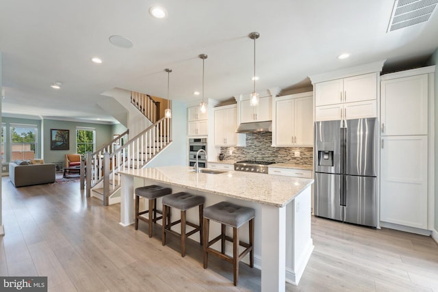 145 Center St S Unit 4, Vienna, VA 22180 - kitchen with appliances with stainless steel finishes, under cabinet range hood, decorative backsplash, a kitchen breakfast bar, and a sink