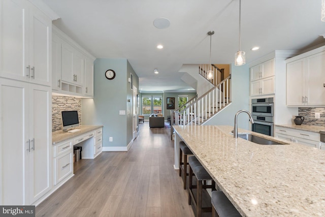 145 Center St S Unit 4, Vienna, VA 22180 - kitchen featuring a sink, tasteful backsplash, a breakfast bar, light wood-style flooring, and white cabinets