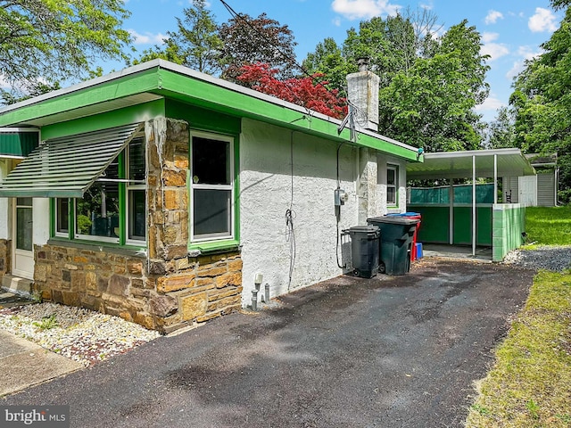 58 Washington Blvd, Norristown, PA 19403 - view of side of home with stone siding, a chimney, asphalt driveway, and stucco siding