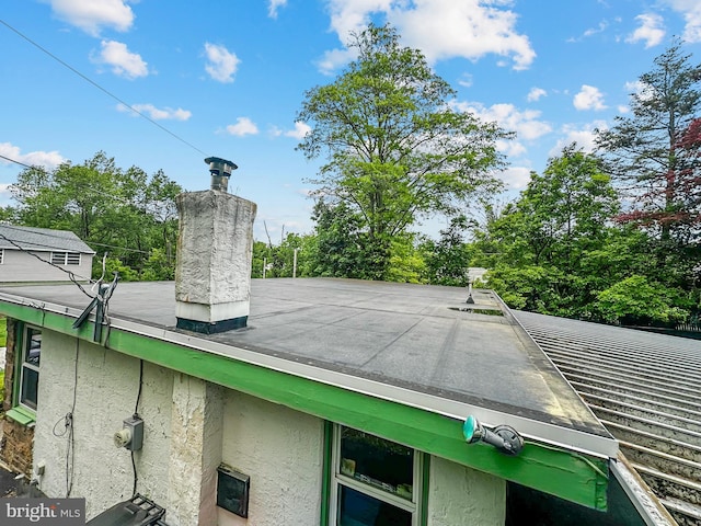 58 Washington Blvd, Norristown, PA 19403 - exterior view of a rolled roof, a chimney, stucco siding, and a tree filled landscape