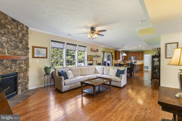 1207 Painted Fern Rd, Denton, MD 21629 - living room with a ceiling fan, wood finished floors, ornamental molding, a fireplace, and a textured ceiling