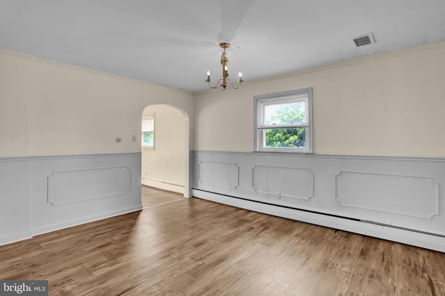 1415 Rockland St, Reading, PA 19604 - spare room featuring a baseboard heating unit, a wainscoted wall, arched walkways, crown molding, and a chandelier