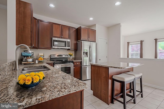 309 Latrobe Dr, Newark, DE 19702 - kitchen featuring appliances with stainless steel finishes, a sink, a breakfast bar area, a center island, and light tile patterned floors