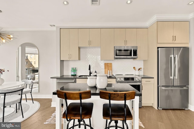 2550 17th St NW Unit 414, Washington, DC 20009 - kitchen featuring appliances with stainless steel finishes, a sink, dark countertops, light wood-style floors, and crown molding