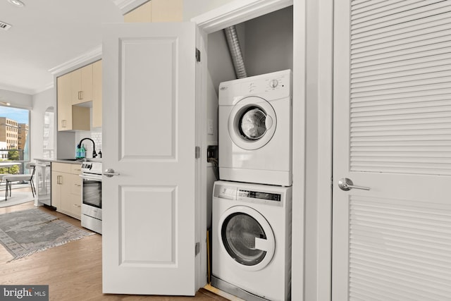 2550 17th St NW Unit 414, Washington, DC 20009 - laundry area with stacked washer and clothes dryer, ornamental molding, and light wood finished floors