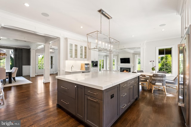 12220 Worthington Rd, Owings Mills, MD 21117 - kitchen featuring white cabinetry, a lit fireplace, crown molding, glass insert cabinets, and open floor plan