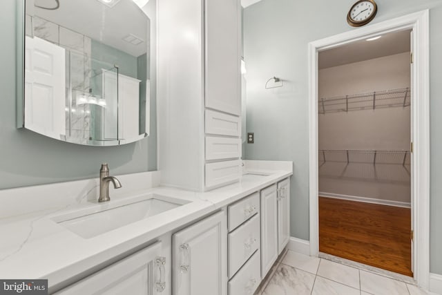 633 Ruxton Rd Unit 75, Solomons, MD 20688 - bathroom featuring double vanity, a stall shower, a spacious closet, marble finish flooring, and baseboards