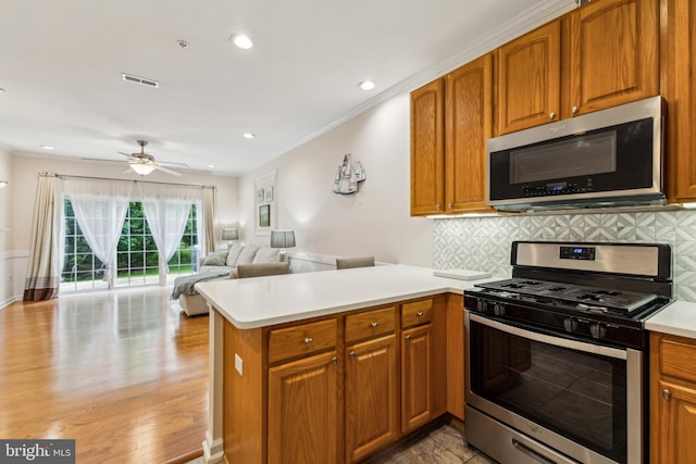 633 Ruxton Rd Unit 75, Solomons, MD 20688 - kitchen featuring stainless steel appliances, a peninsula, decorative backsplash, light countertops, and brown cabinets