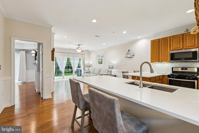 633 Ruxton Rd Unit 75, Solomons, MD 20688 - kitchen featuring appliances with stainless steel finishes, a sink, ornamental molding, a kitchen breakfast bar, and wood finished floors