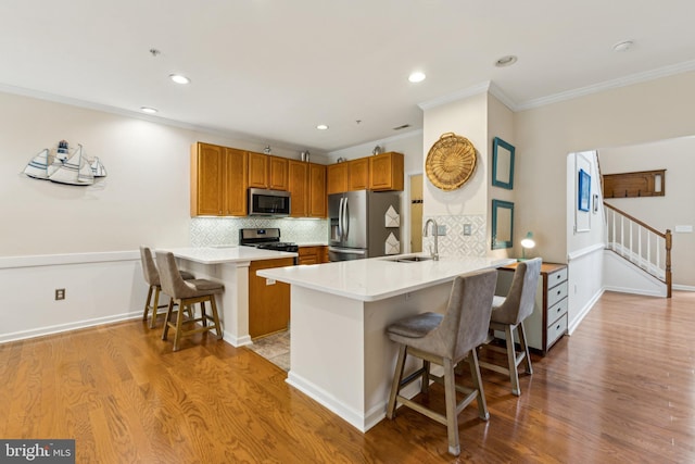 633 Ruxton Rd Unit 75, Solomons, MD 20688 - kitchen with stainless steel appliances, a peninsula, a sink, crown molding, and a breakfast bar area