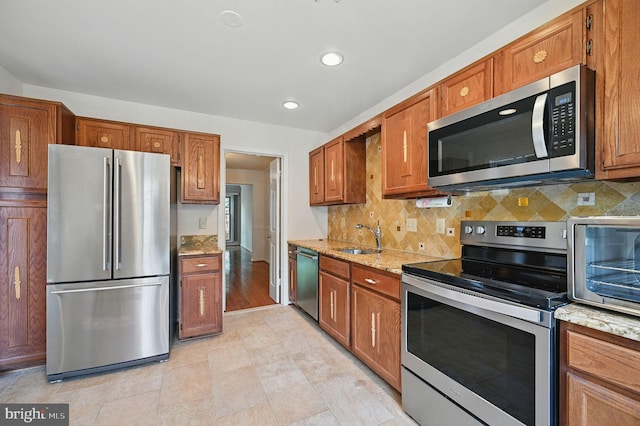 11707 Critton Cir, Woodbridge, VA 22192 - kitchen with appliances with stainless steel finishes, brown cabinetry, backsplash, light stone countertops, and recessed lighting