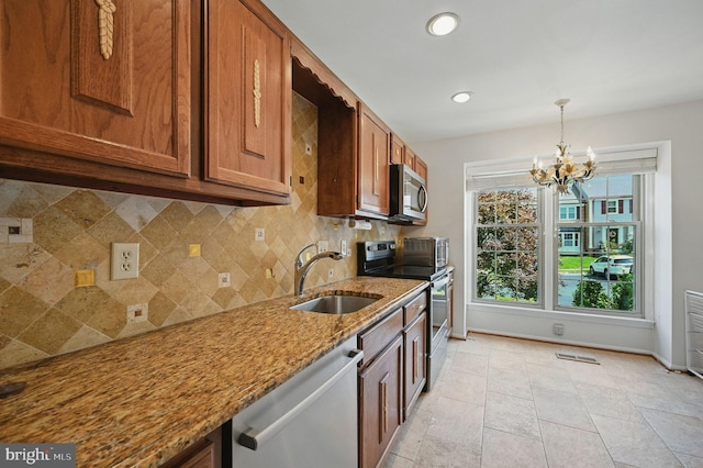 11707 Critton Cir, Woodbridge, VA 22192 - kitchen featuring stainless steel appliances, decorative backsplash, a chandelier, light stone countertops, and brown cabinetry