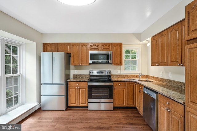 8530 Raglan Rd, Vienna, VA 22182 - kitchen featuring appliances with stainless steel finishes, dark stone countertops, brown cabinetry, and dark wood-style flooring