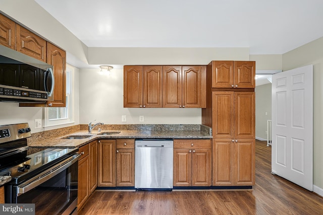 8530 Raglan Rd, Vienna, VA 22182 - kitchen featuring stainless steel appliances, dark stone counters, brown cabinets, and dark wood-type flooring