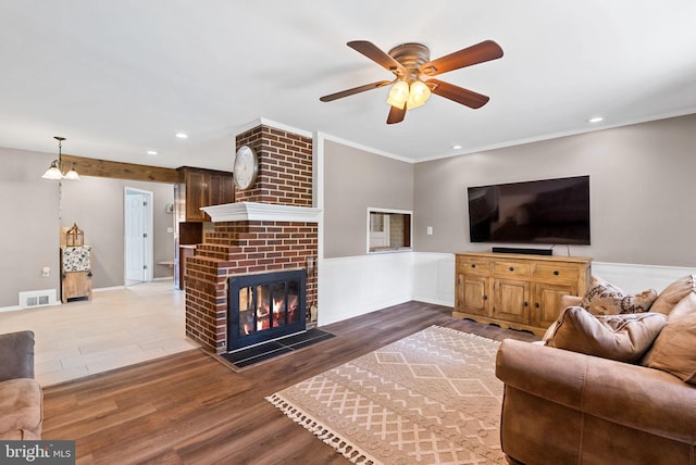 7407 Falmouth St, Springfield, VA 22150 - living room with ceiling fan, wood finished floors, a wainscoted wall, ornamental molding, and a brick fireplace