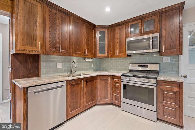7407 Falmouth St, Springfield, VA 22150 - kitchen featuring appliances with stainless steel finishes, tasteful backsplash, light stone counters, and glass insert cabinets