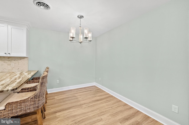 12542 Torquay Rd, Ocean City, MD 21842 - dining area featuring a chandelier, light wood-style floors, and baseboards