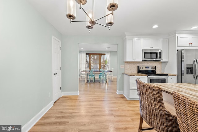 12542 Torquay Rd, Ocean City, MD 21842 - kitchen with appliances with stainless steel finishes, a chandelier, light wood finished floors, baseboards, and white cabinetry
