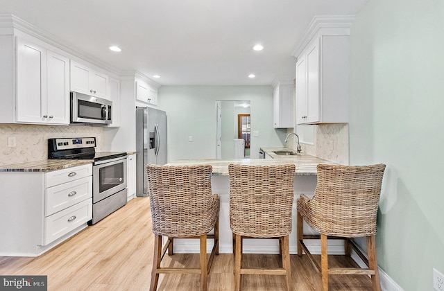 12542 Torquay Rd, Ocean City, MD 21842 - kitchen featuring appliances with stainless steel finishes, a sink, tasteful backsplash, light wood-style floors, and recessed lighting