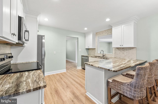 12542 Torquay Rd, Ocean City, MD 21842 - kitchen featuring appliances with stainless steel finishes, a sink, white cabinets, backsplash, and light wood finished floors