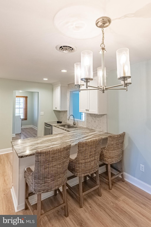 12542 Torquay Rd, Ocean City, MD 21842 - kitchen featuring light wood-style floors, white cabinets, a sink, baseboards, and a kitchen bar