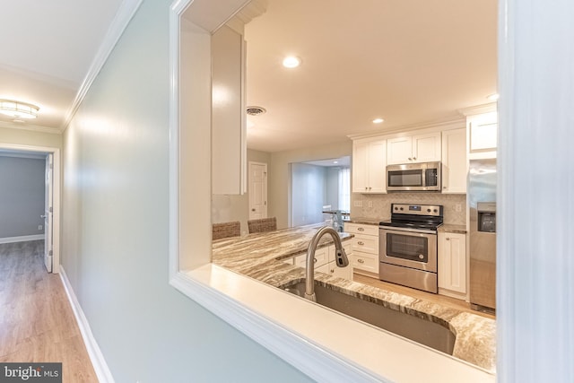 12542 Torquay Rd, Ocean City, MD 21842 - kitchen with appliances with stainless steel finishes, a sink, crown molding, white cabinetry, and tasteful backsplash