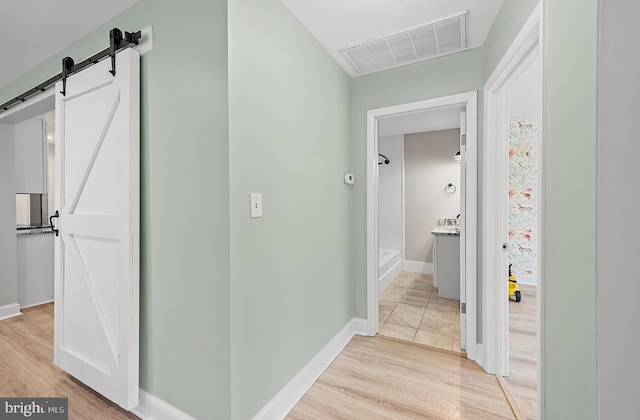 12542 Torquay Rd, Ocean City, MD 21842 - corridor featuring a barn door, light wood finished floors, and baseboards