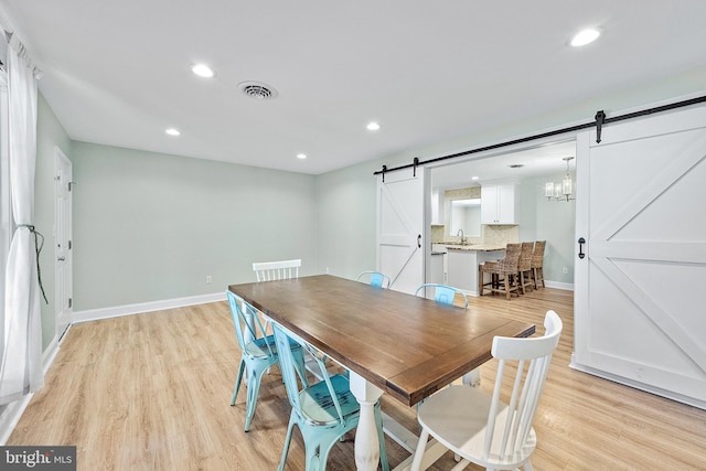 12542 Torquay Rd, Ocean City, MD 21842 - dining space with a barn door, light wood-style flooring, recessed lighting, and baseboards