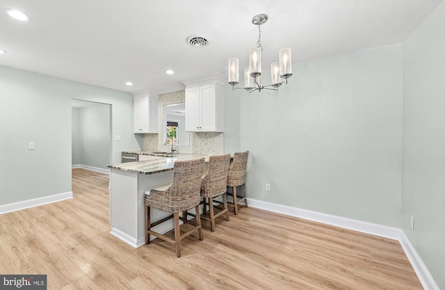 12542 Torquay Rd, Ocean City, MD 21842 - kitchen with recessed lighting, white cabinetry, light wood-type flooring, a kitchen breakfast bar, and baseboards