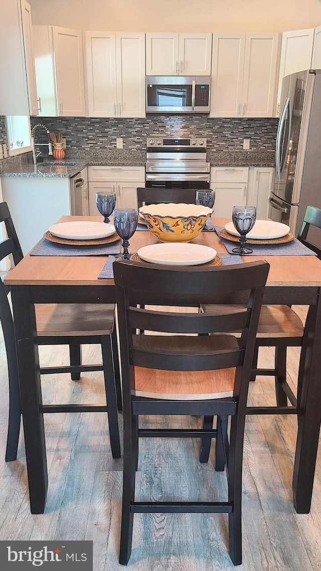 511 S Kent St, Winchester, VA 22601 - kitchen featuring appliances with stainless steel finishes, white cabinets, tasteful backsplash, and light wood finished floors