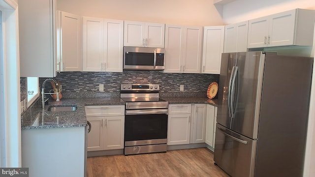 511 S Kent St, Winchester, VA 22601 - kitchen with appliances with stainless steel finishes, a sink, tasteful backsplash, light wood finished floors, and dark stone countertops