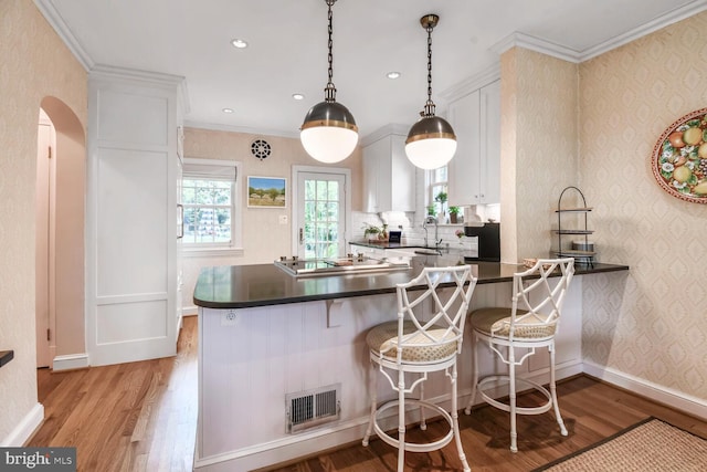 4212 Ingomar St NW, Washington, DC 20015 - kitchen with dark countertops, light wood finished floors, white cabinetry, black electric stovetop, and a sink