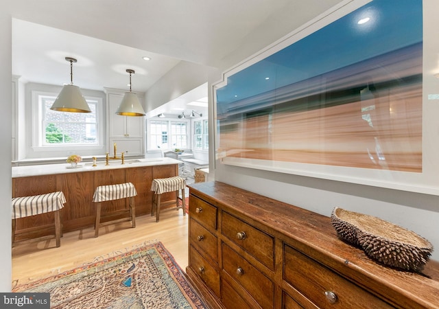 7006 Meadow Ln, Chevy Chase, MD 20815 - kitchen featuring light wood-type flooring, pendant lighting, a kitchen bar, and brown cabinets